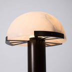 Close view of the lit dome of this Clérachic table lamp, with its dark bronze ring and spoked support above the stem.