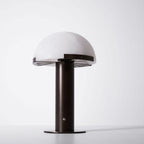 Dark bronze-coloured Clérachic table lamp at a slight angle against a white backdrop, with the spoked support visible under the dome.