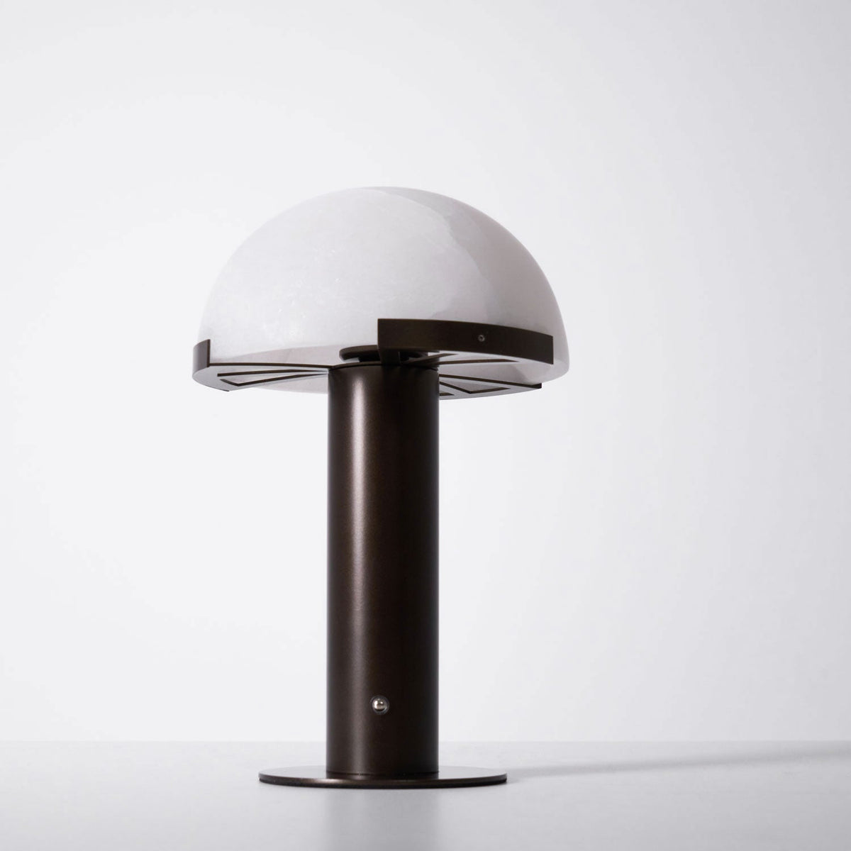 Dark bronze-coloured Clérachic table lamp at a slight angle against a white backdrop, with the spoked support visible under the dome.
