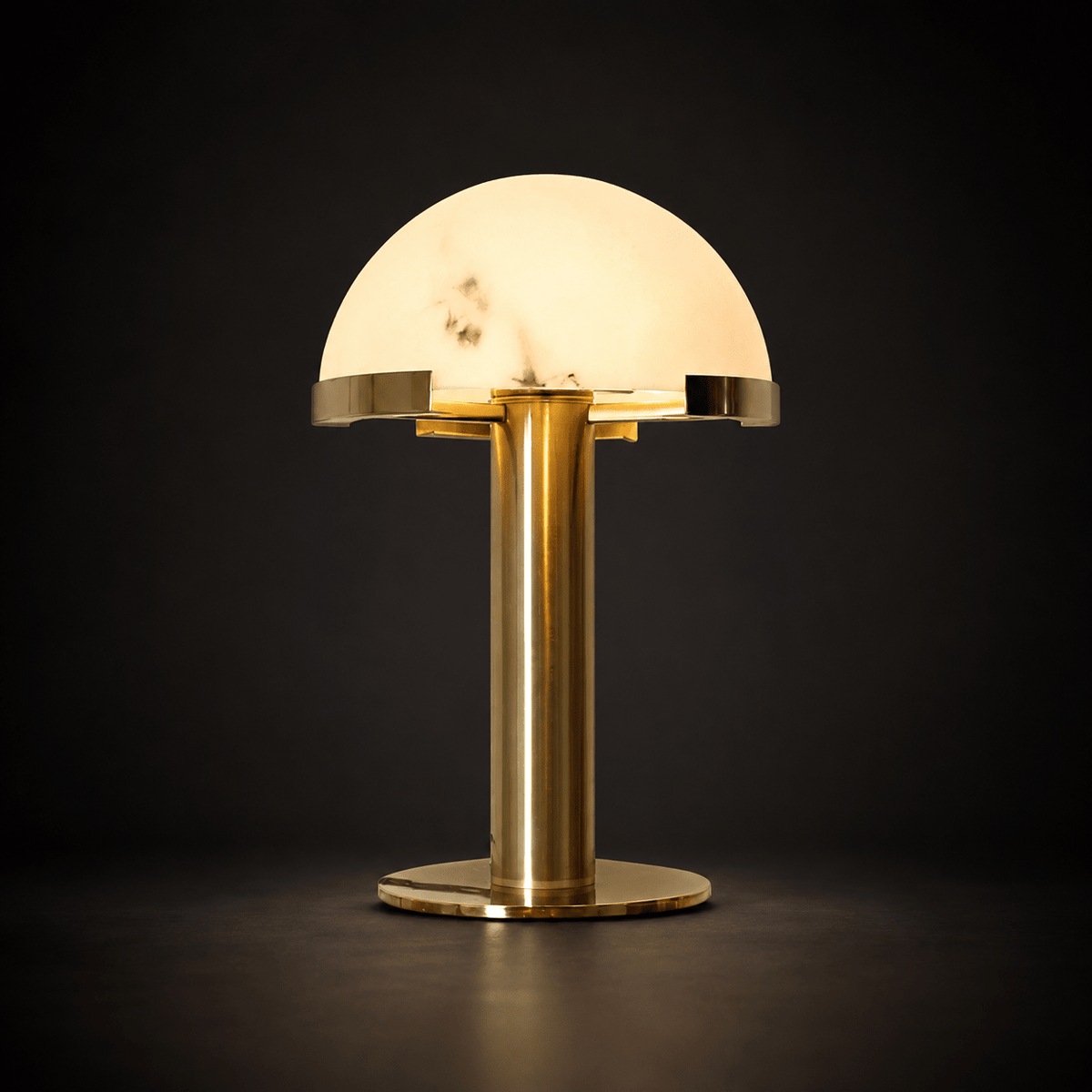 Gold Clérachic table lamp lit against a dark charcoal backdrop, the veined dome glowing and the brass base reflecting the light.