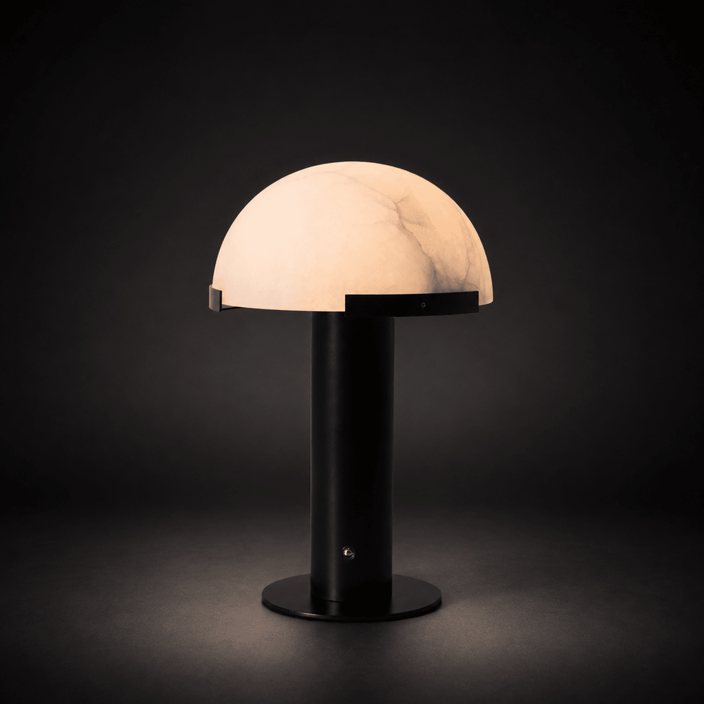 Black Clérachic table lamp lit in the dark, the dome glowing pink-white with fine grey veins above a round black base.