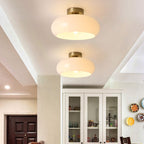 Two white Clérachic Puffed Oval Glass Ceiling Lights lighting a hallway above a glazed white dresser.