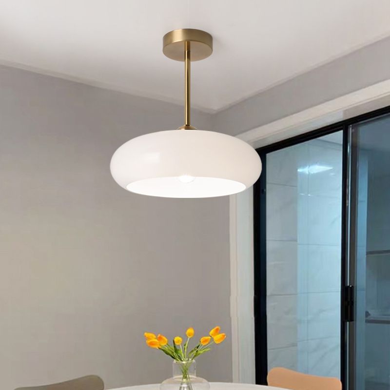 White Clérachic Puffed Oval Glass Ceiling Light on its brass drop rod above a dining table by the balcony doors.