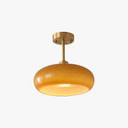 Studio view of the Clérachic Puffed Oval Glass Ceiling Light in orange glass, lit on its short brushed brass drop rod.