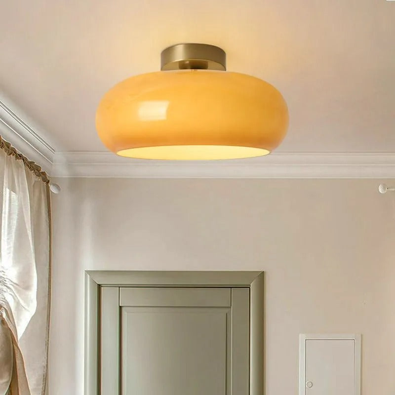 Orange Clérachic Puffed Oval Glass Ceiling Light sitting flush on the ceiling above a sage-green door and cream curtain.
