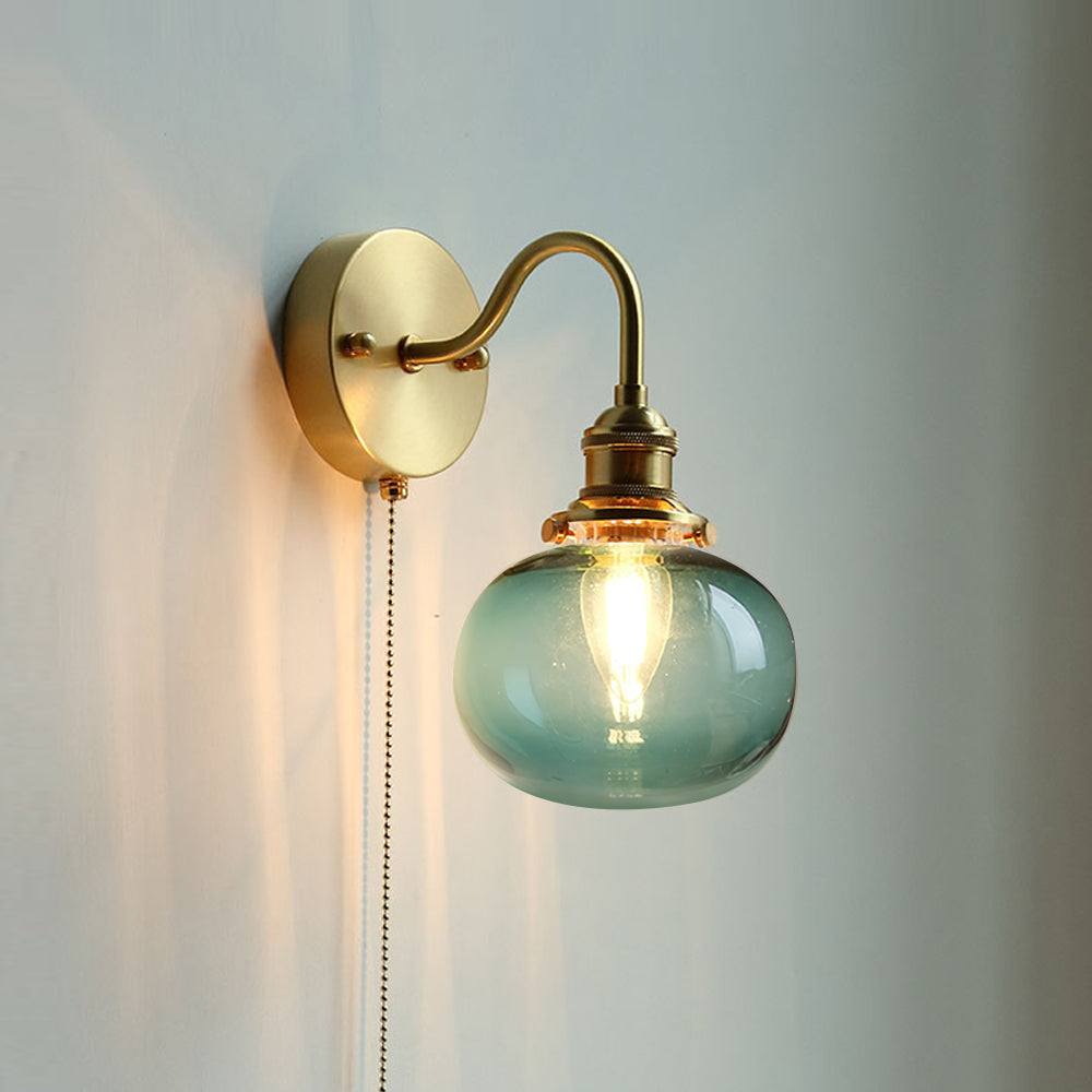Blue seeded glass globe on the Clérachic Pull-Chain Brass Wall Sconce, fine bubbles caught in the glass as the bulb glows behind it.