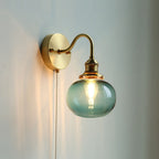 Blue seeded glass globe on the Clérachic Pull-Chain Brass Wall Sconce, fine bubbles caught in the glass as the bulb glows behind it.