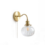 Studio view of the Clérachic Pull-Chain Brass Wall Sconce on white, showing the round backplate, gooseneck arm and clear fluted globe.
