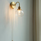 Clérachic Pull-Chain Brass Wall Sconce glowing in a corner, the long brass bead chain running down the wall within easy reach.