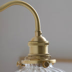 Close-up of the Clérachic sconce's brass socket, knurled thumbscrews and gallery ring that hold the glass globe in place.