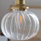 Detail of the clear fluted globe on the Clérachic brass wall sconce, a filament LED bulb throwing fine vertical streaks of light.