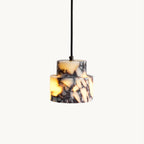 Two-tier Clérachic pendant in purple-veined white marble on a black cord, glowing amber, on a plain off-white backdrop.