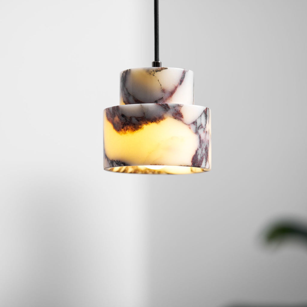 Close view of this Clérachic pendant's stepped marble shade, lit from inside so the veining shows amber and plum.