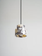 Underside view of the marble Clérachic pendant, with the bulb visible inside and a pale grey wall behind it.