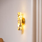 Lit marble shade of this Clérachic wall light glowing amber against a pale wall, with a soft curtain fold to the right.