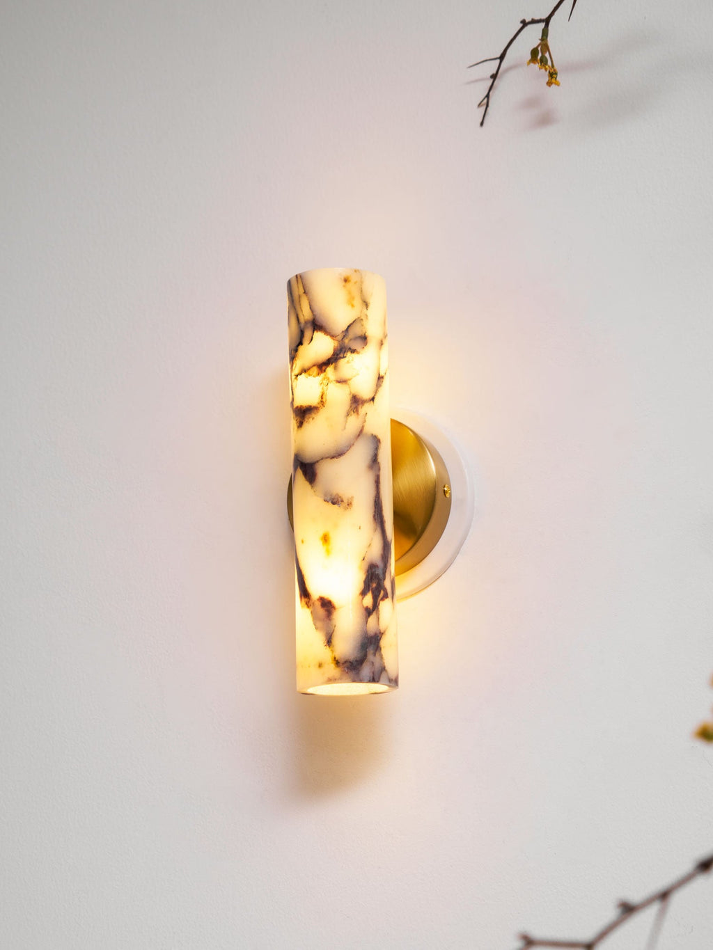 Lit Clérachic wall light seen close, with the shade's purple veining glowing and its lower opening showing warm light.