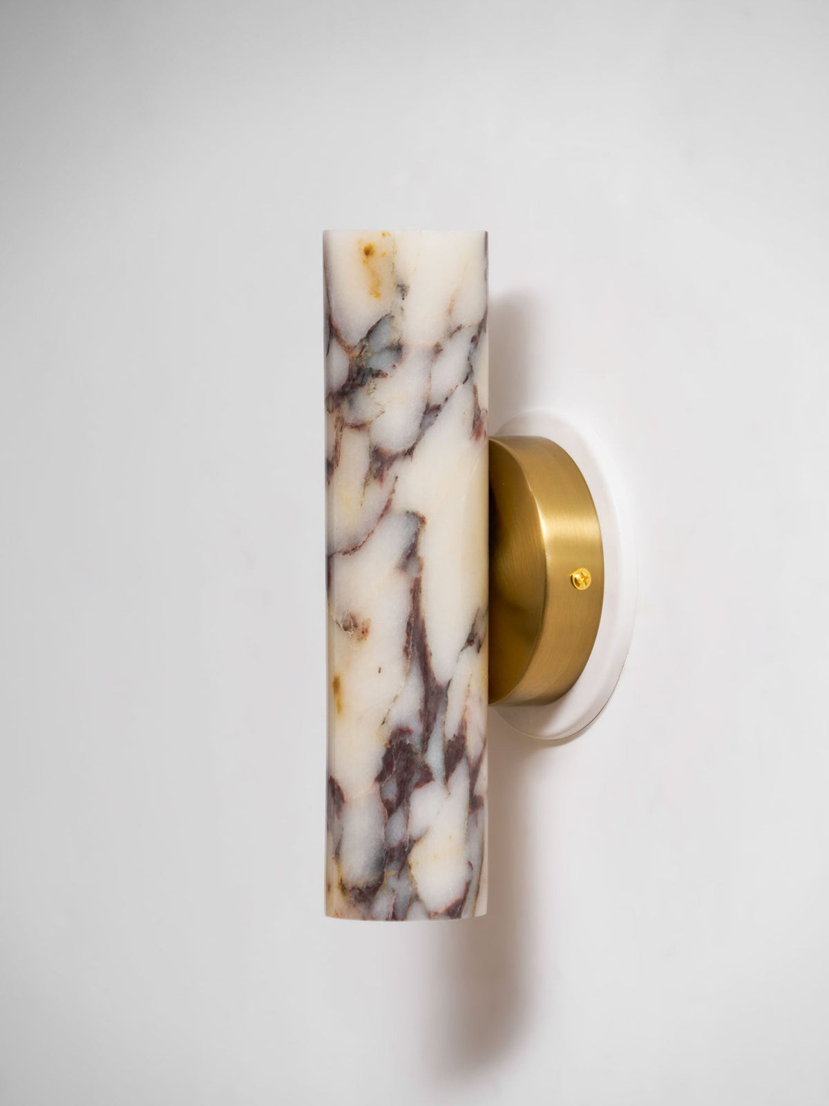 Side view of this Clérachic wall light, the cylindrical marble shade offset from its brass wall plate on a white wall.