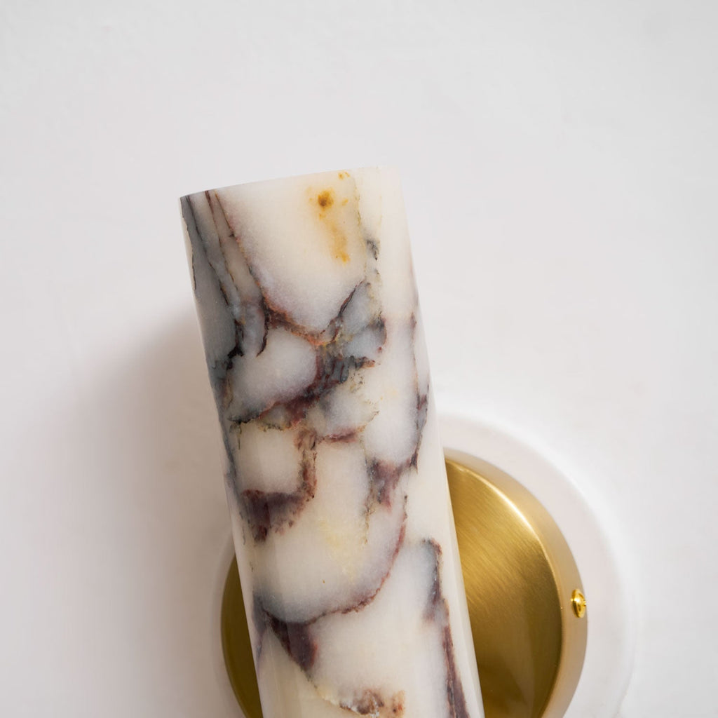 Close view of the purple and gold veining on the marble shade of this Clérachic wall light, with the brass plate behind it.