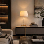 This Clérachic table lamp sits on a stone-topped console with a wooden bowl and books, lit warmly against a framed landscape.