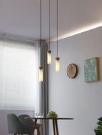 Three Clérachic Quiver Pendant Lights hung at staggered heights over a small dining table, alabaster columns lit beside a shuttered window.
