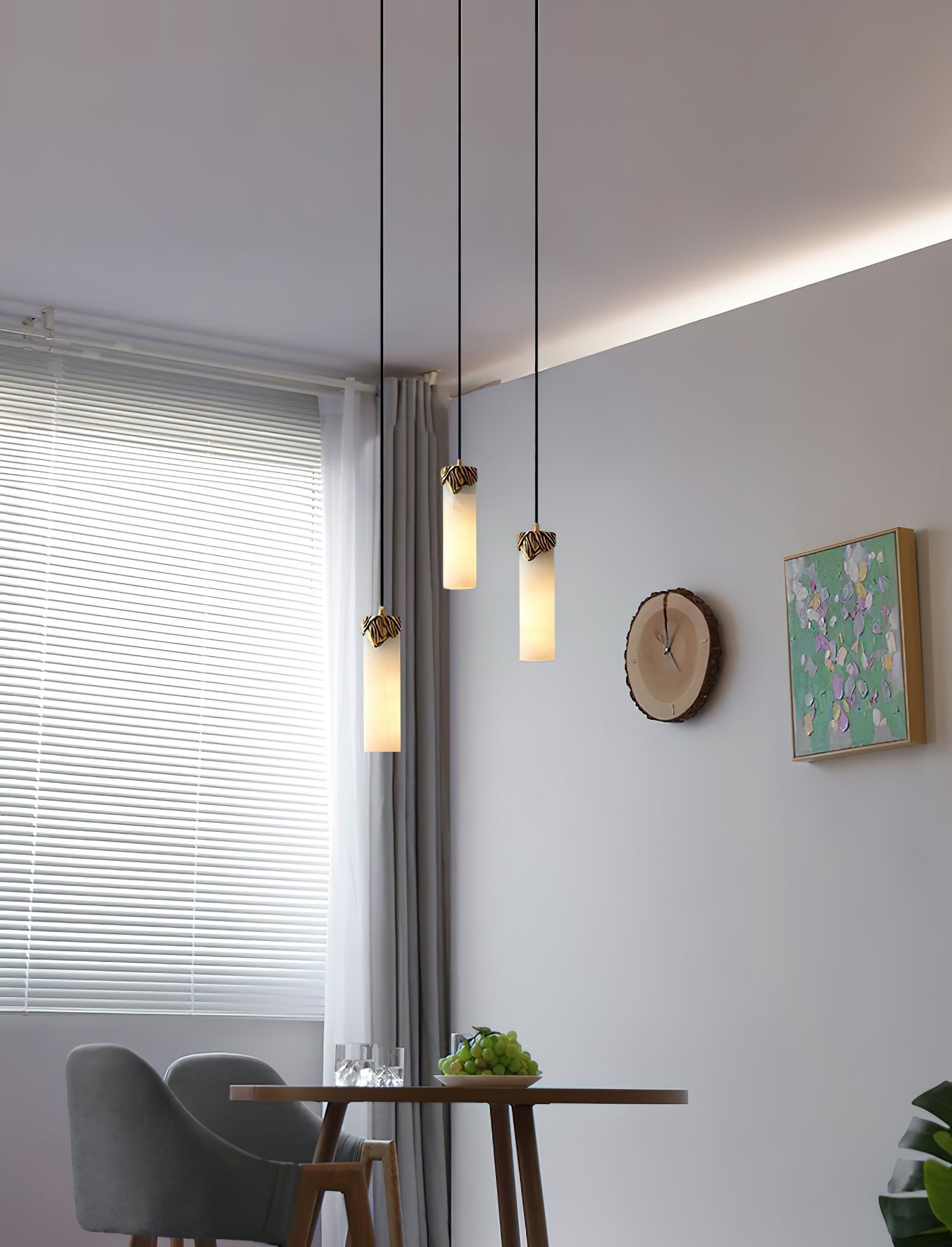 Three Clérachic Quiver Pendant Lights hung at staggered heights over a small dining table, alabaster columns lit beside a shuttered window.