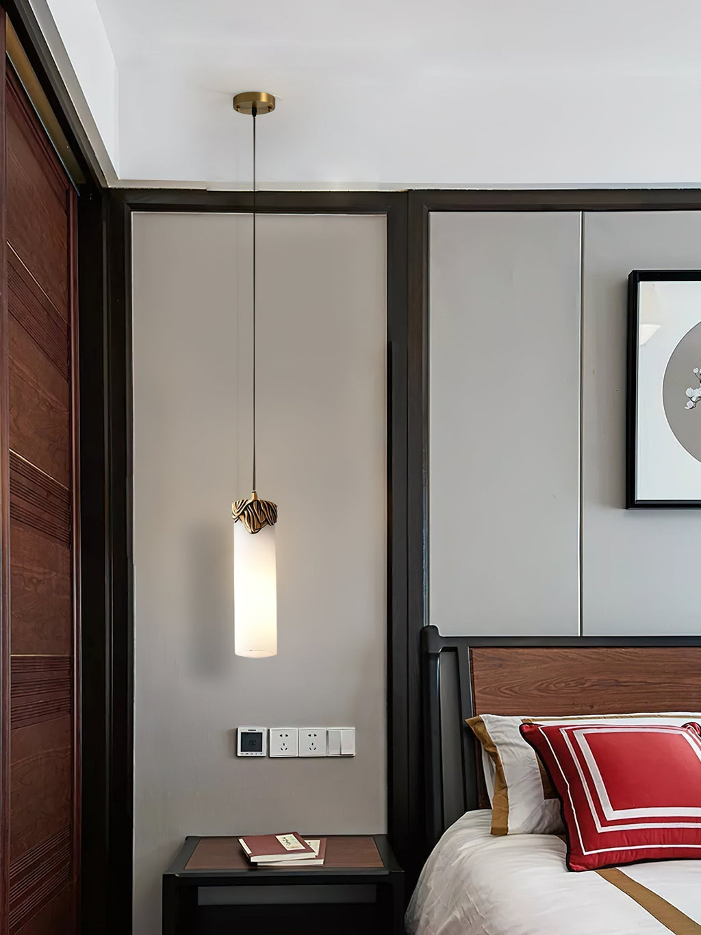 Clérachic Quiver Pendant Light dropped over a dark wood bedside table in a bedroom, taking the place of a lamp and freeing the whole surface.