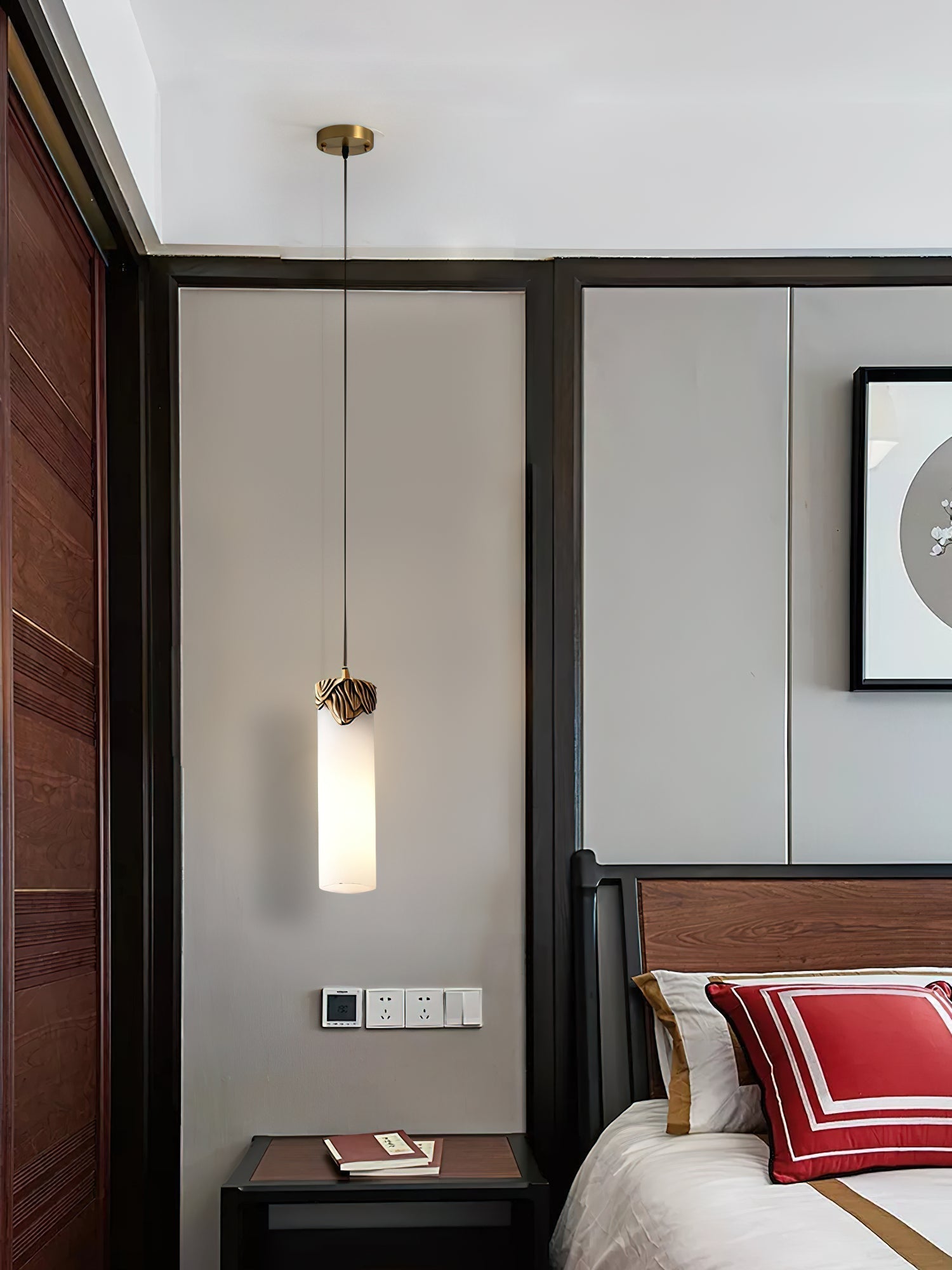 Clérachic Quiver Pendant Light dropped over a dark wood bedside table in a bedroom, taking the place of a lamp and freeing the whole surface.