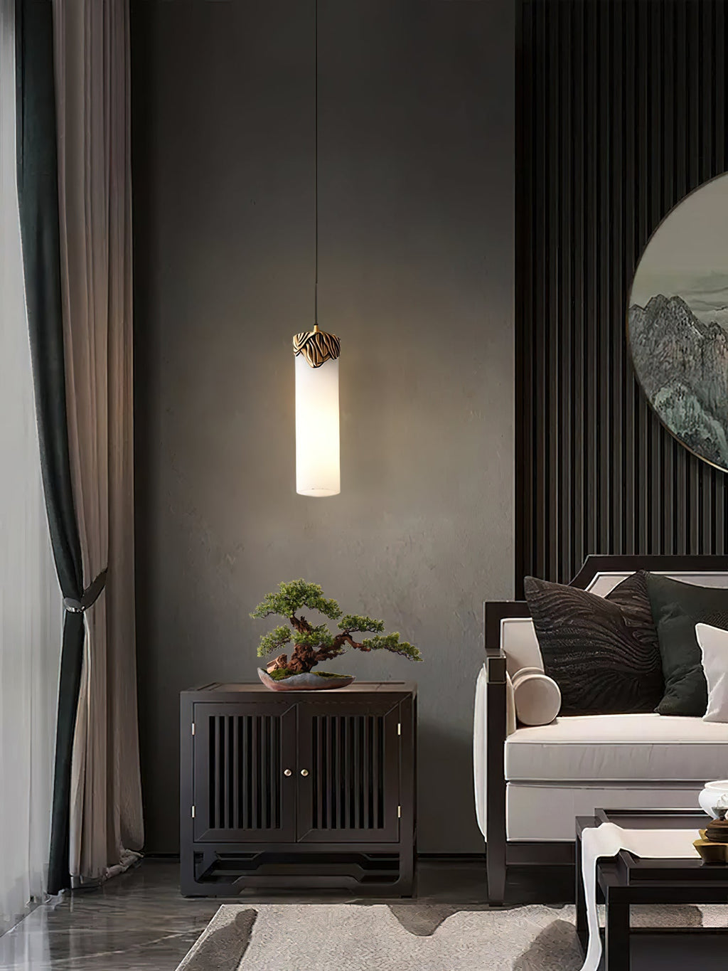 Clérachic Quiver Pendant Light glowing against a deep grey plaster wall, lighting a bonsai on the cabinet below in a quiet sitting room.