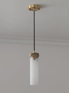 Unlit Clérachic Quiver Pendant Light installed on a plain ceiling, showing the pale matte stone, brass canopy and black fabric cord.