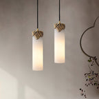 Both sizes of the Clérachic Quiver Pendant Light lit side by side on a limewash wall, the short and tall columns hung at different heights.