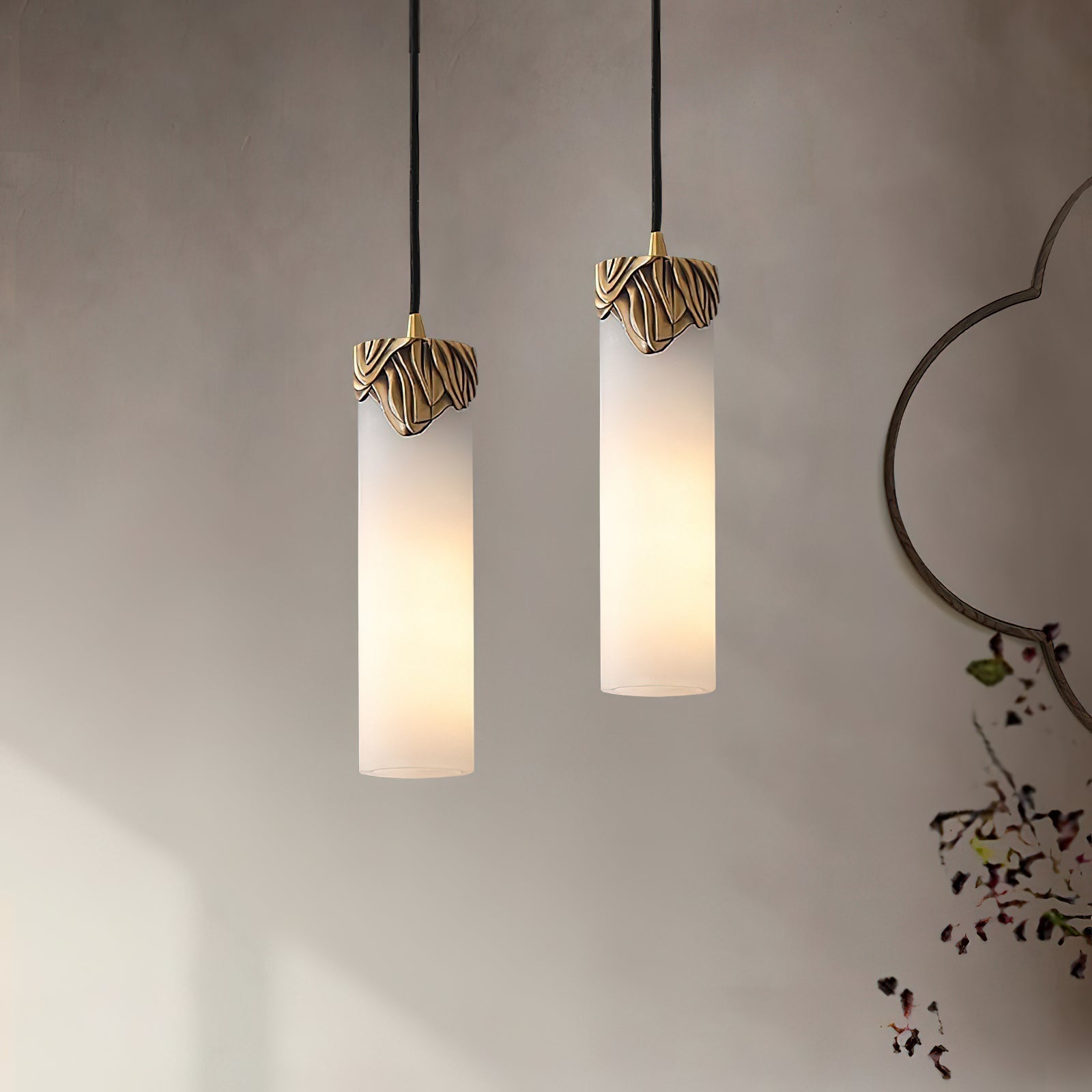 Both sizes of the Clérachic Quiver Pendant Light lit side by side on a limewash wall, the short and tall columns hung at different heights.