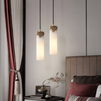 Two Clérachic Quiver Pendant Lights lit at staggered heights over a bedside table, freeing the surface beside a curtained window.