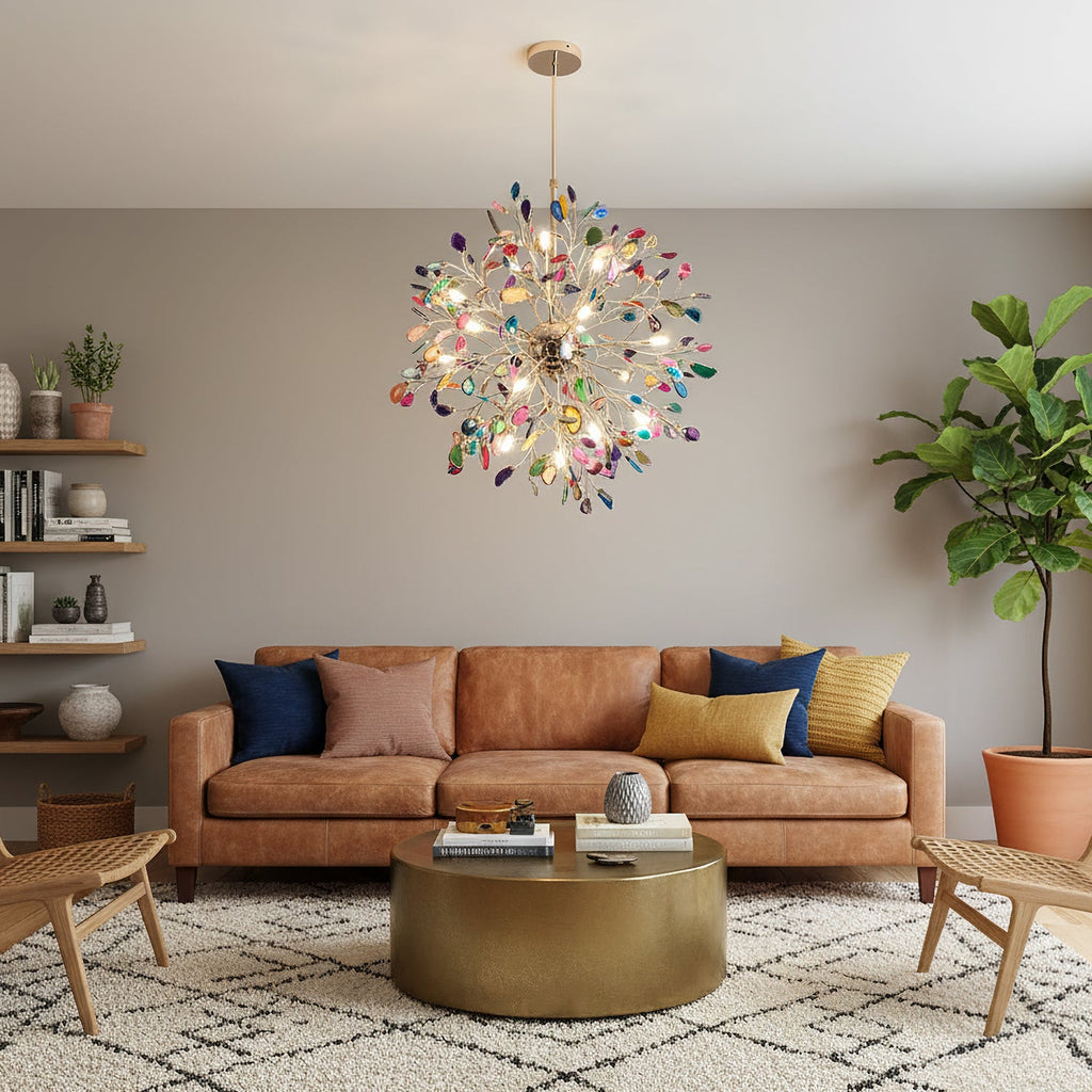 Lit Clérachic agate chandelier above a tan leather sofa and a round brass coffee table, on a taupe wall with open shelves.