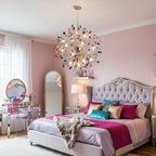 Clérachic agate chandelier above a bed with a tufted headboard and a magenta throw, in a pink bedroom with a mirrored dressing table.
