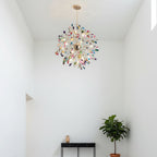 Lit Clérachic agate chandelier in a white room with a high ceiling, above a black console, a fig tree and a small vase.