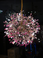 Lit Clérachic chandelier with pink agate slices on gold branches, photographed in a dark room.