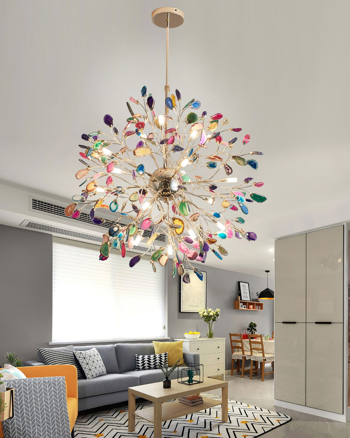 Clérachic multicolour agate chandelier above a grey sofa and a wooden coffee table, in a living room with an orange armchair.