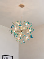 Teal agate Clérachic chandelier lit above a pale wall, with a framed picture just visible at the lower edge.