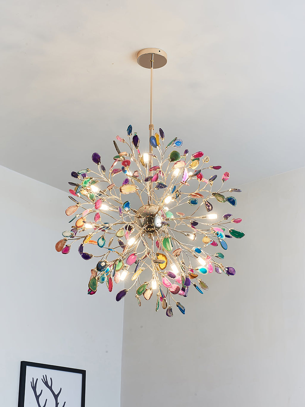 Multicolour agate Clérachic chandelier lit under a pale ceiling, with a black and white print at the lower left.