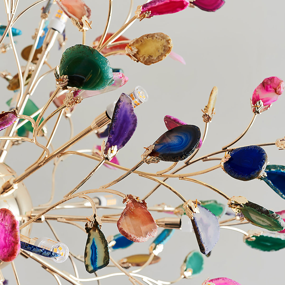 Close view of green, blue, purple and amber agate slices set on thin gold branches of this Clérachic chandelier.