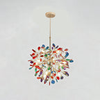 Clérachic agate chandelier with red, blue and green slices on a pale grey backdrop, lit, hanging from a slim gold rod.