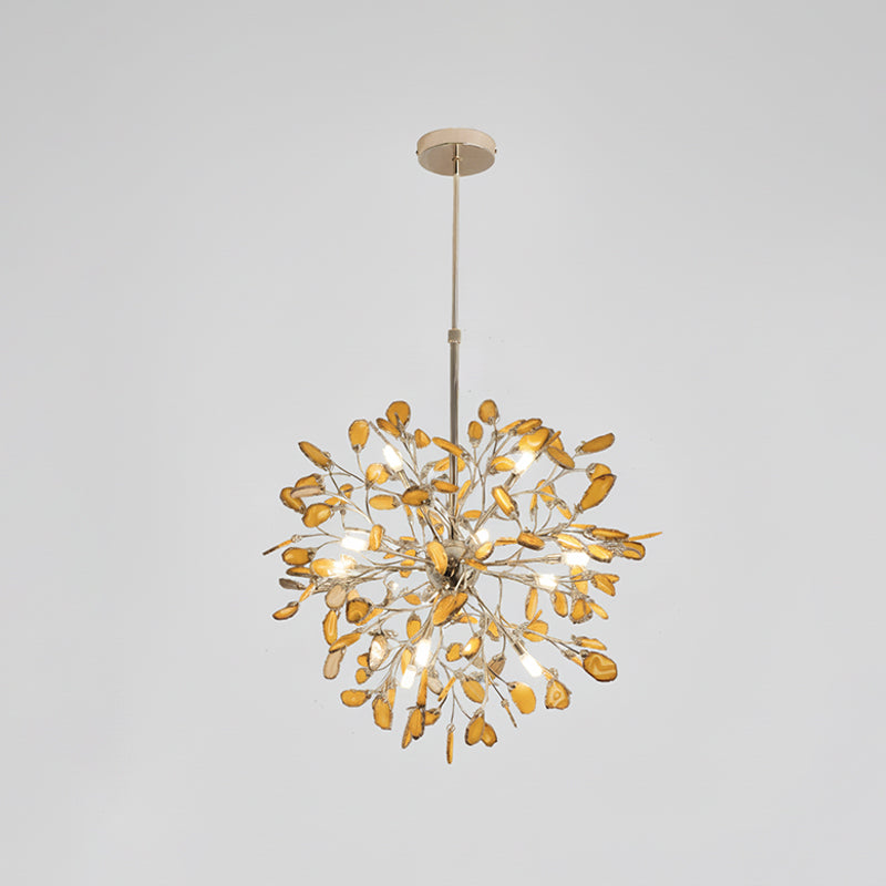 Amber agate Clérachic chandelier on a pale grey backdrop, lit, hanging from a gold rod and round canopy.