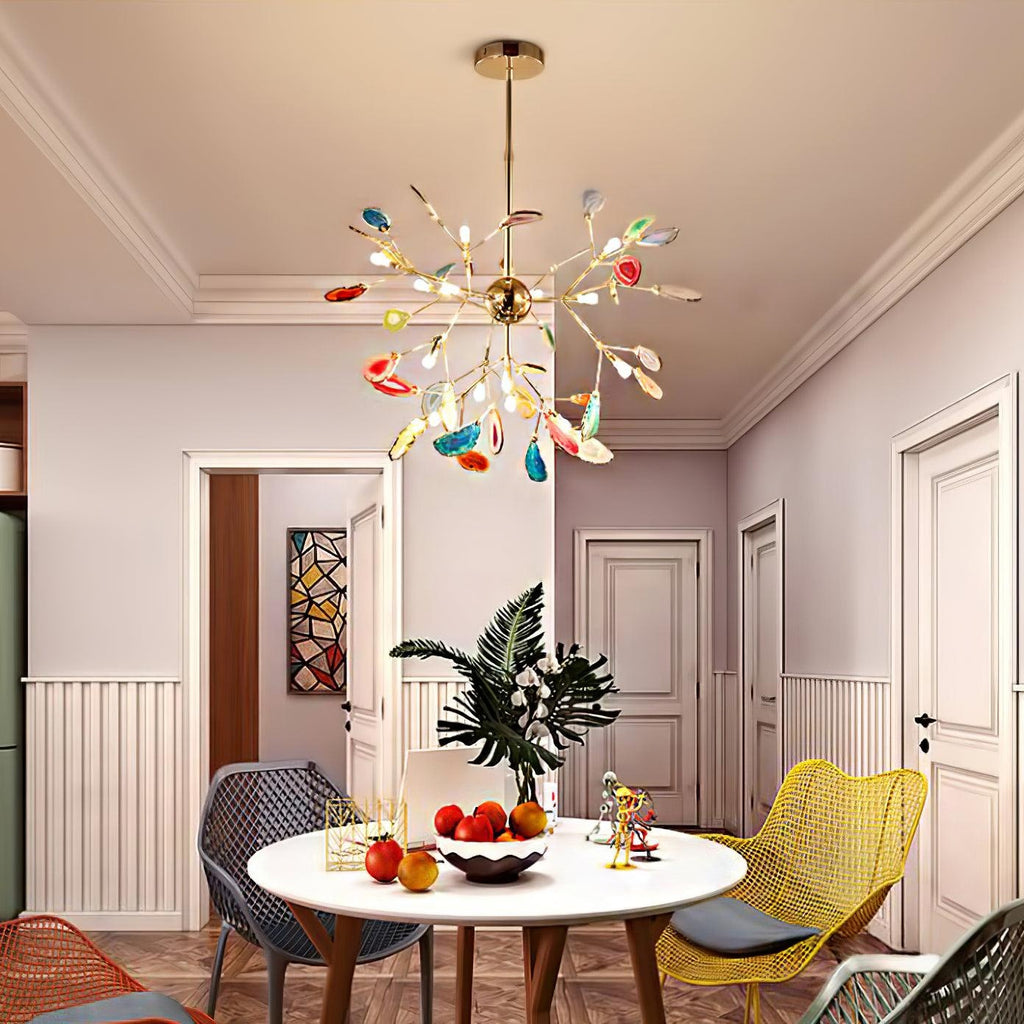 A Clérachic agate chandelier above a round white dining table in a pink room, with white panelled doors and yellow chairs.