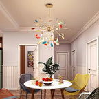 A Clérachic agate chandelier above a round white dining table in a pink room, with white panelled doors and yellow chairs.