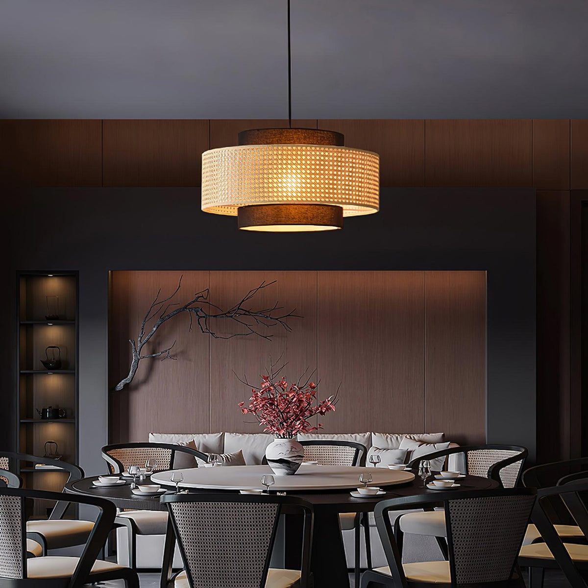 A rattan-banded Clérachic pendant hangs over a round dark table in a moody dining room with a dark wood wall.