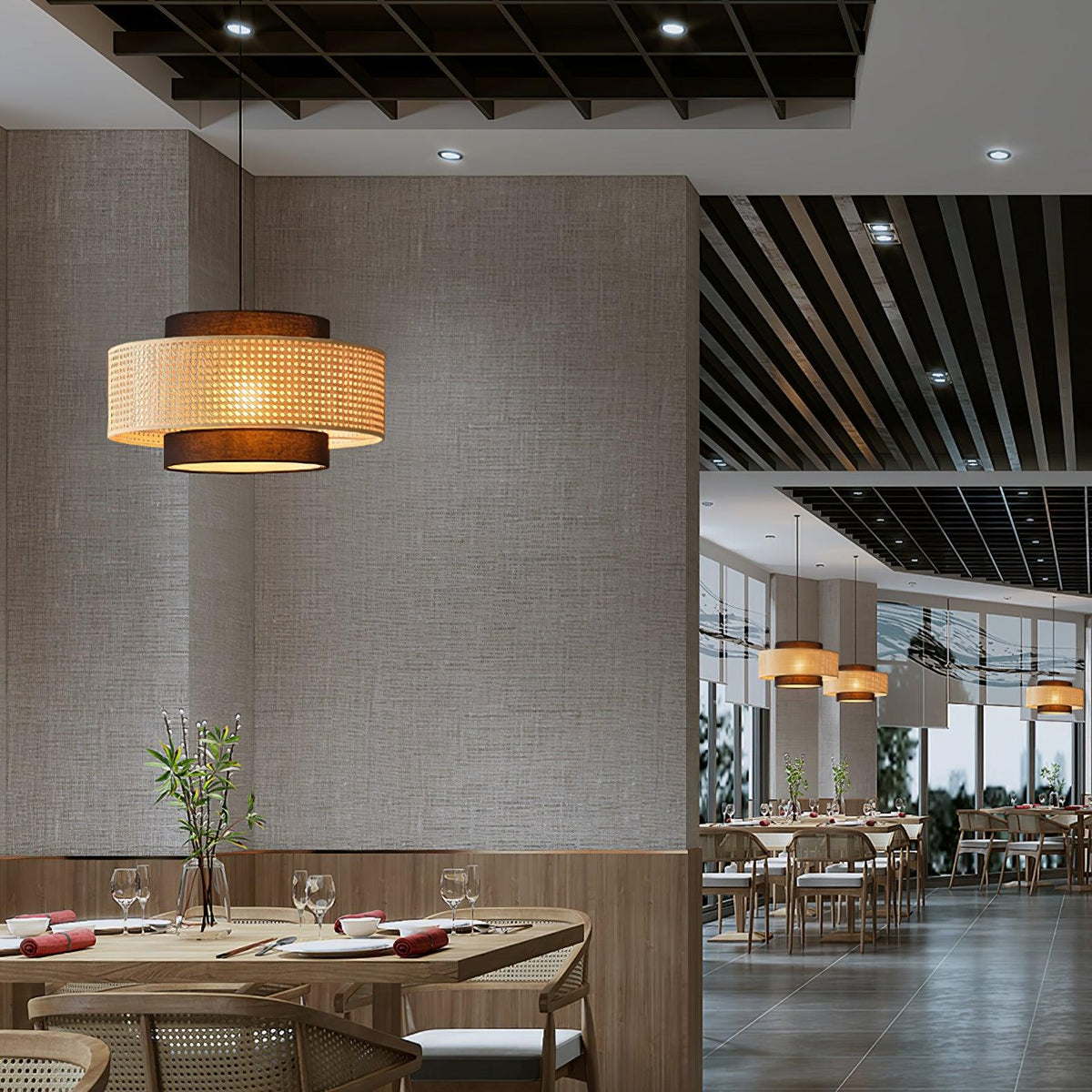 A Clérachic pendant with a rattan drum hangs beside a textured wall, with a dining room and ceiling slats beyond.