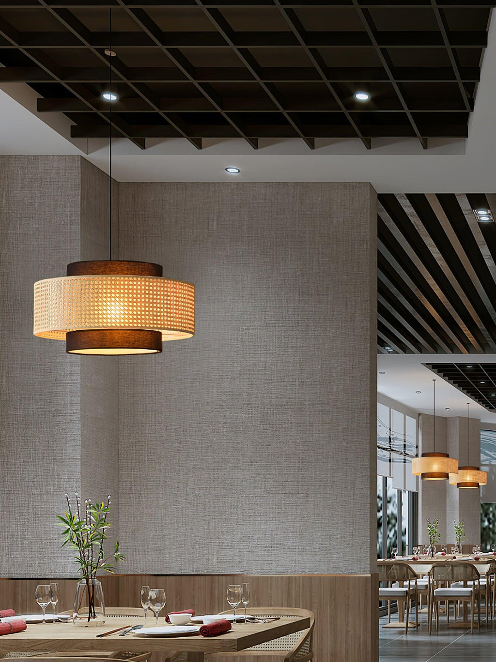 A taller view of a rattan Clérachic pendant by a textured wall, with a set table and a dining room in the distance.