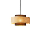 A Clérachic pendant with a perforated rattan drum and brown fabric tiers, seen at a slight angle on white.