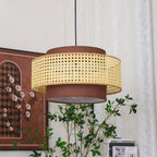 Another close view of the Clérachic pendant from below, with the cane drum above its brown fabric base and a framed print behind.