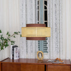 A Clérachic pendant with a woven cane band hangs against a lace curtain and a pale blue shutter, above a wooden sideboard.